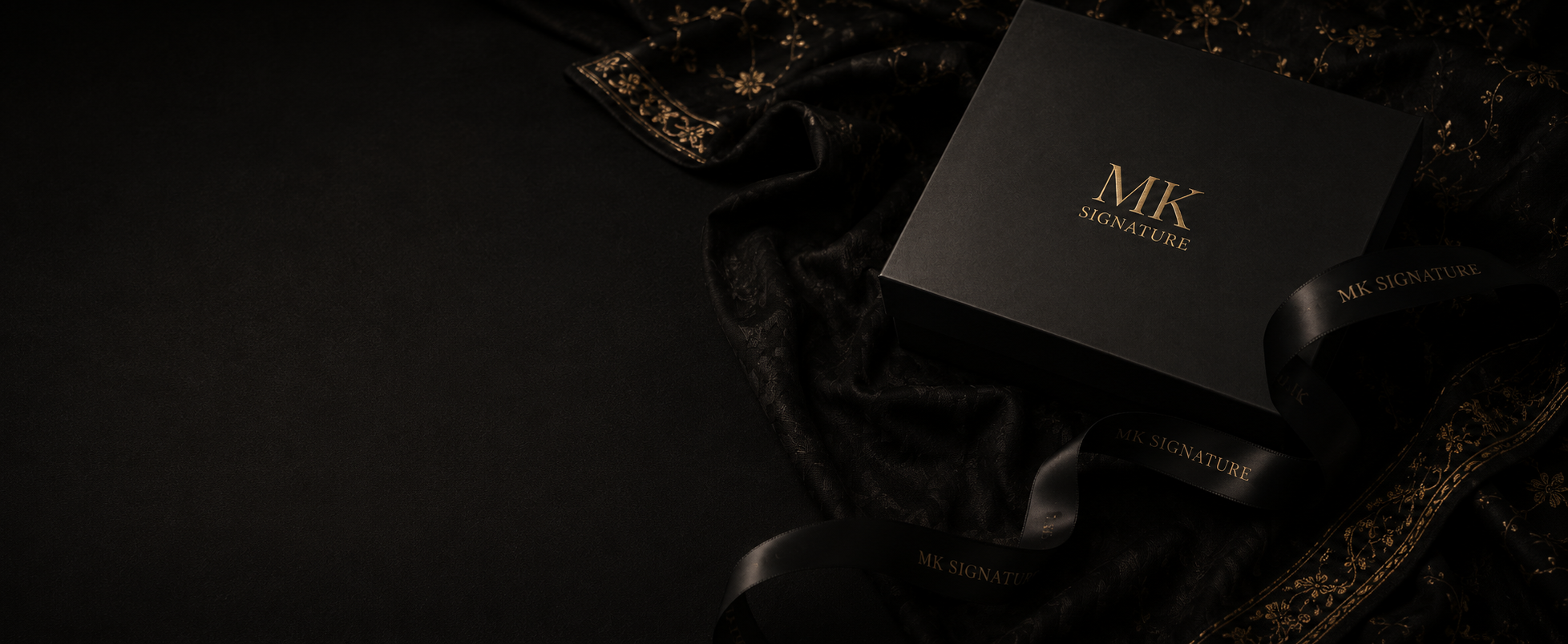 MK Signature packaging displayed on black embroidered fabric